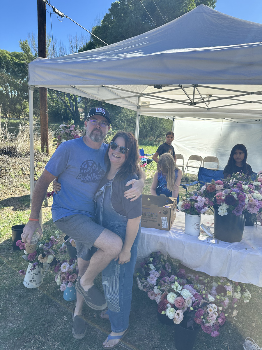 Chris and Elizabeth smiling together at an outdoor flower stand